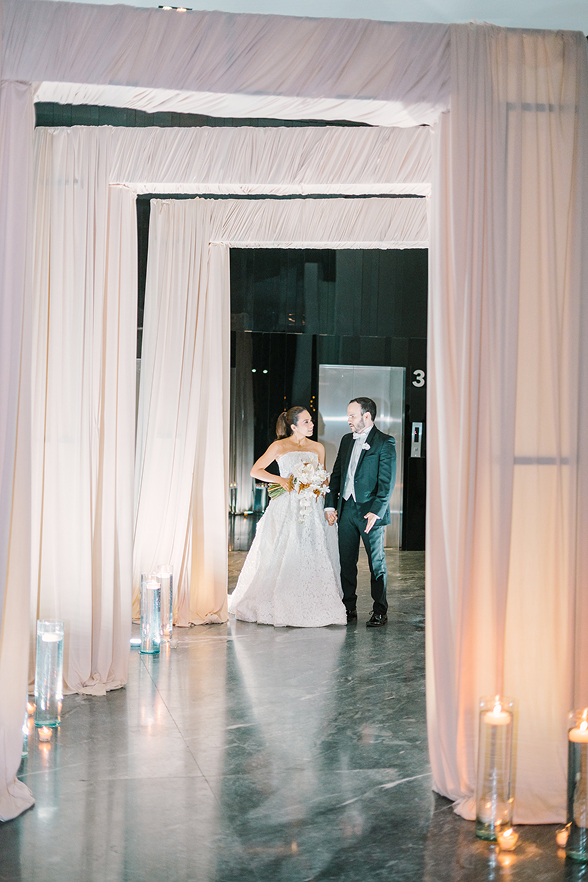 Pareja de novios en un pasillo con telas y velas.