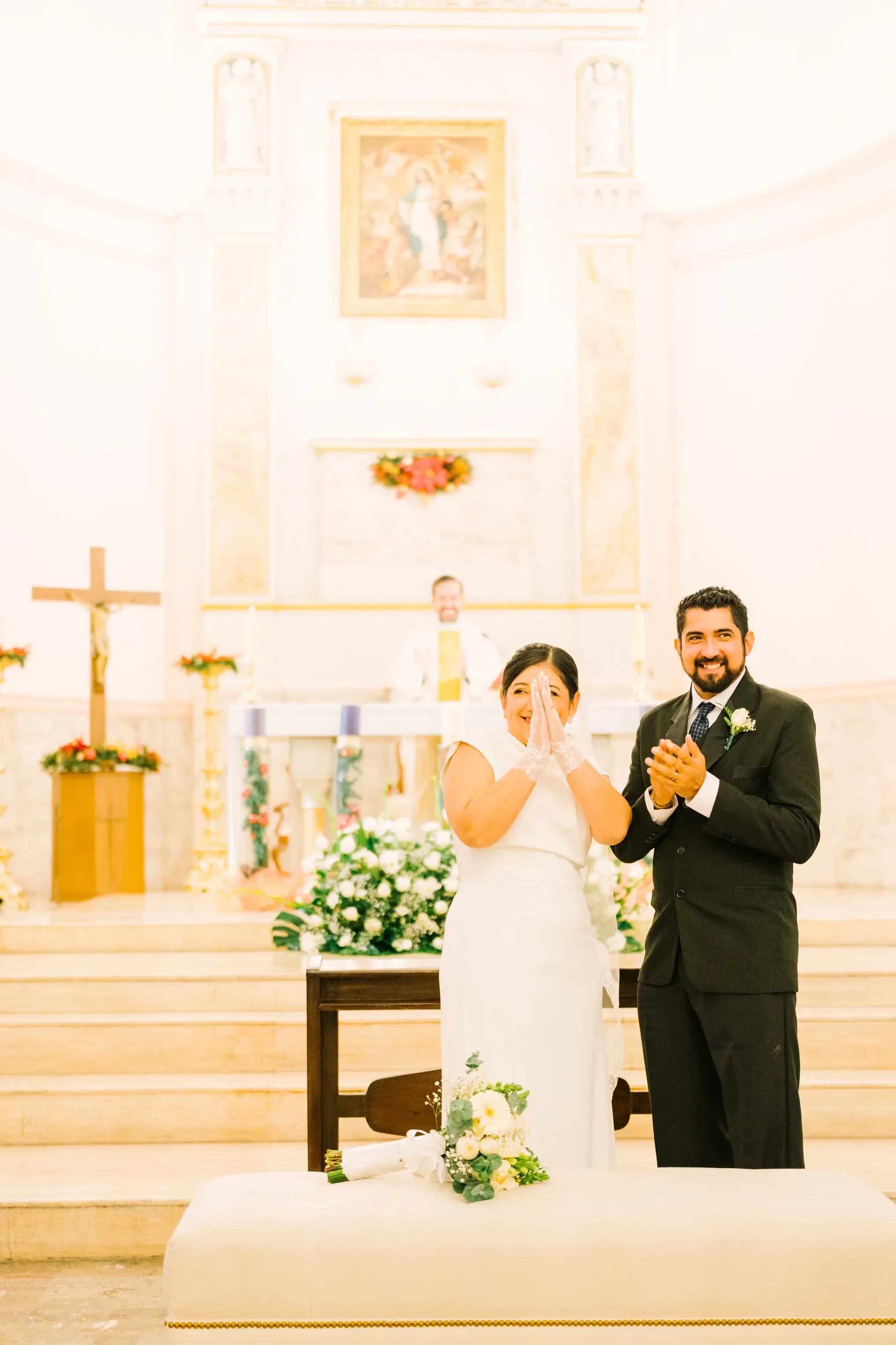 Amy y Jorge aplaudiendo emocionados frente al altar de la Iglesia de la Luz en Monterrey durante la ceremonia religiosa
