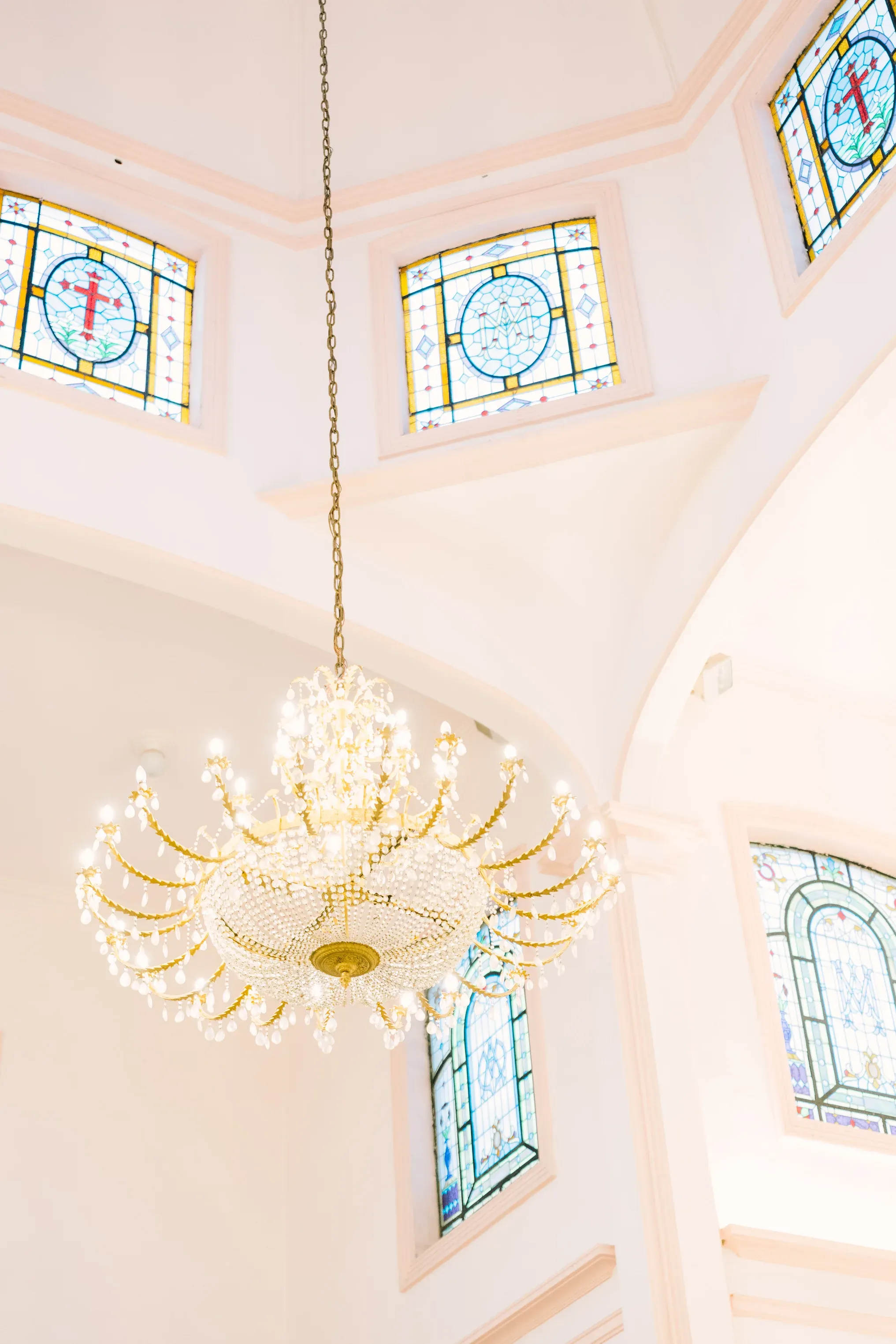 Candelabro de cristal dorado colgante en la Iglesia de la Luz con vitrales coloridos de motivos religiosos