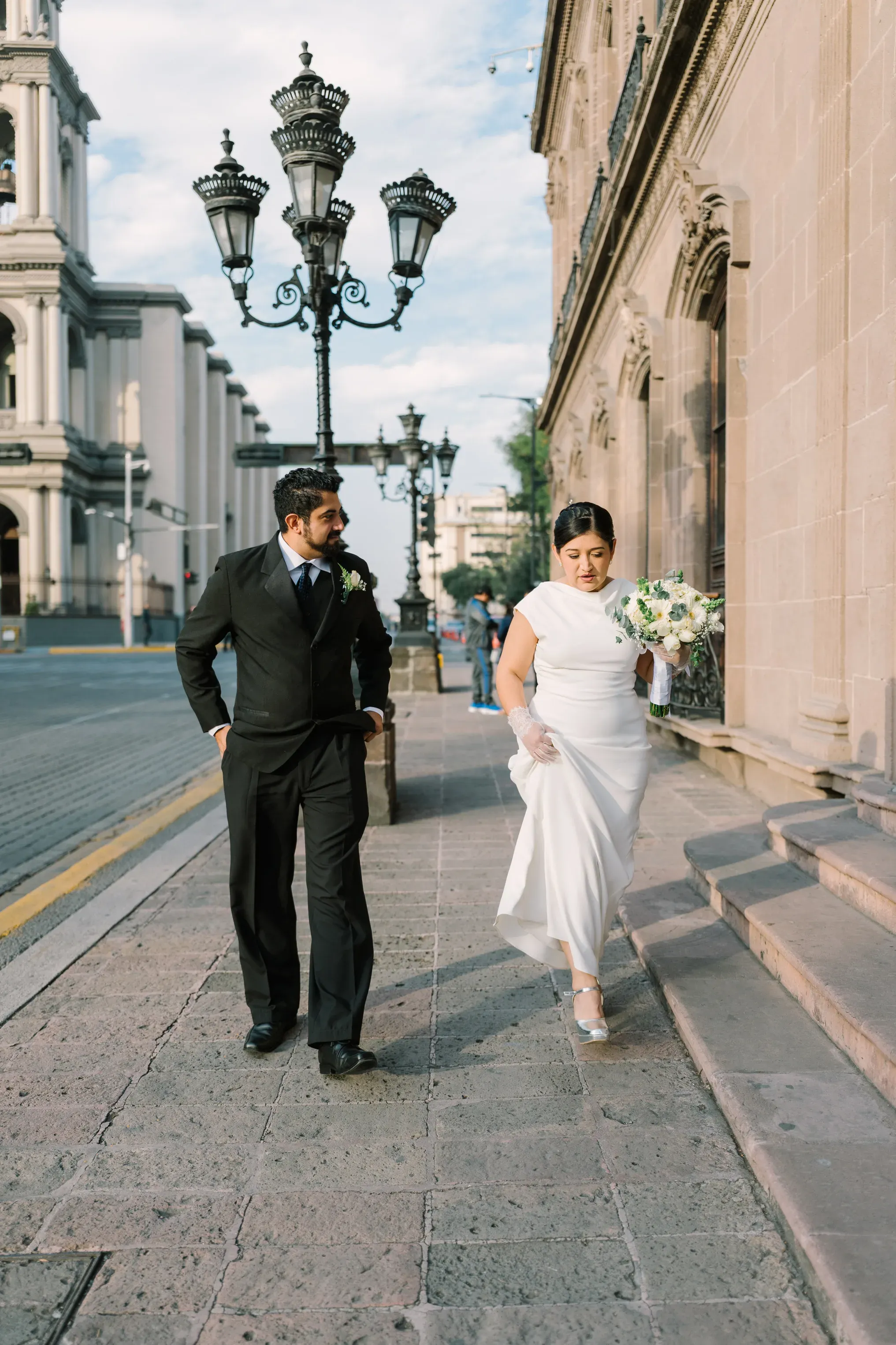 Amy y Jorge caminando por la acera del centro histórico de Monterrey entre faroles de hierro forjado