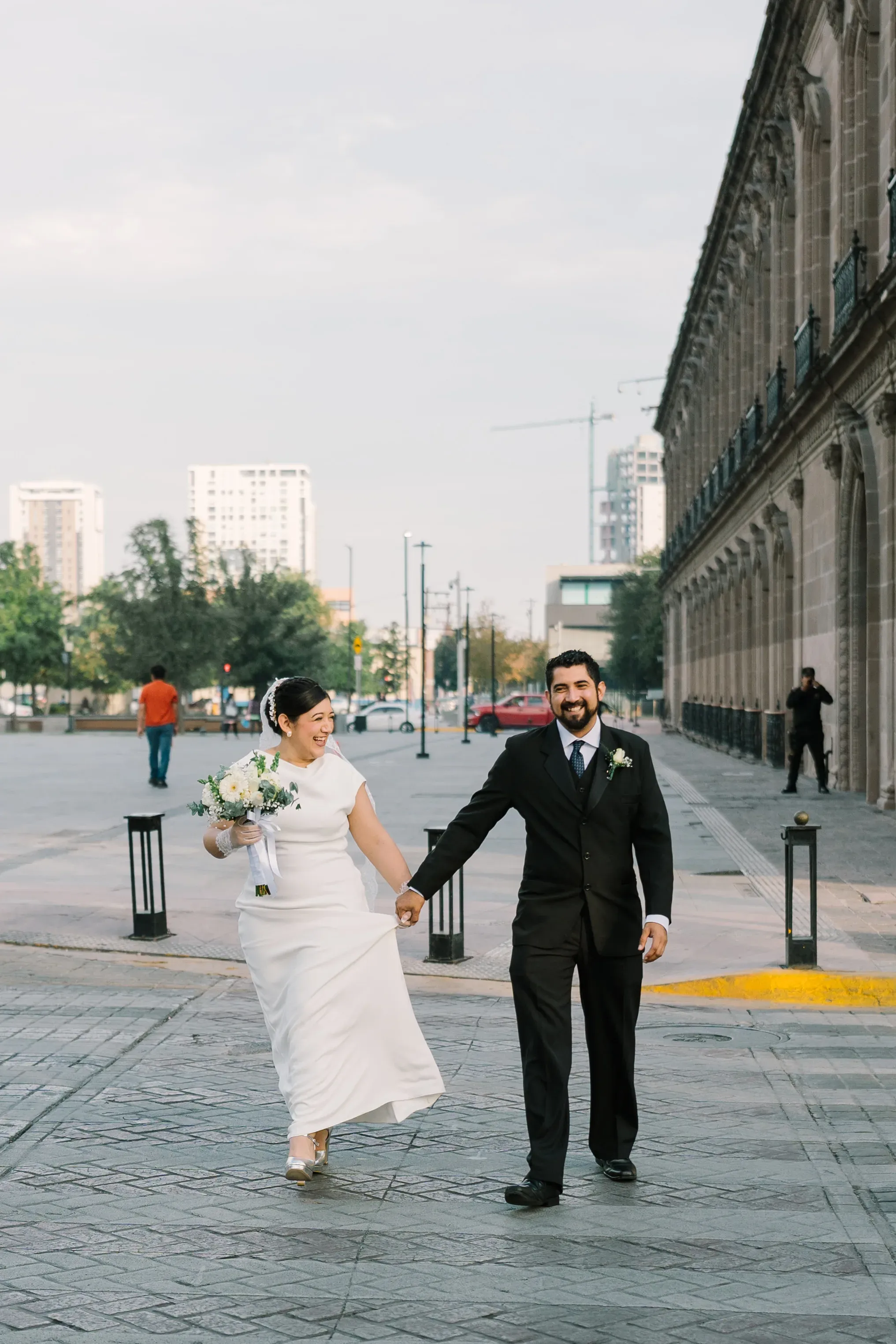 Amy y Jorge tomados de la mano caminando frente a edificio neoclásico en el centro de Monterrey