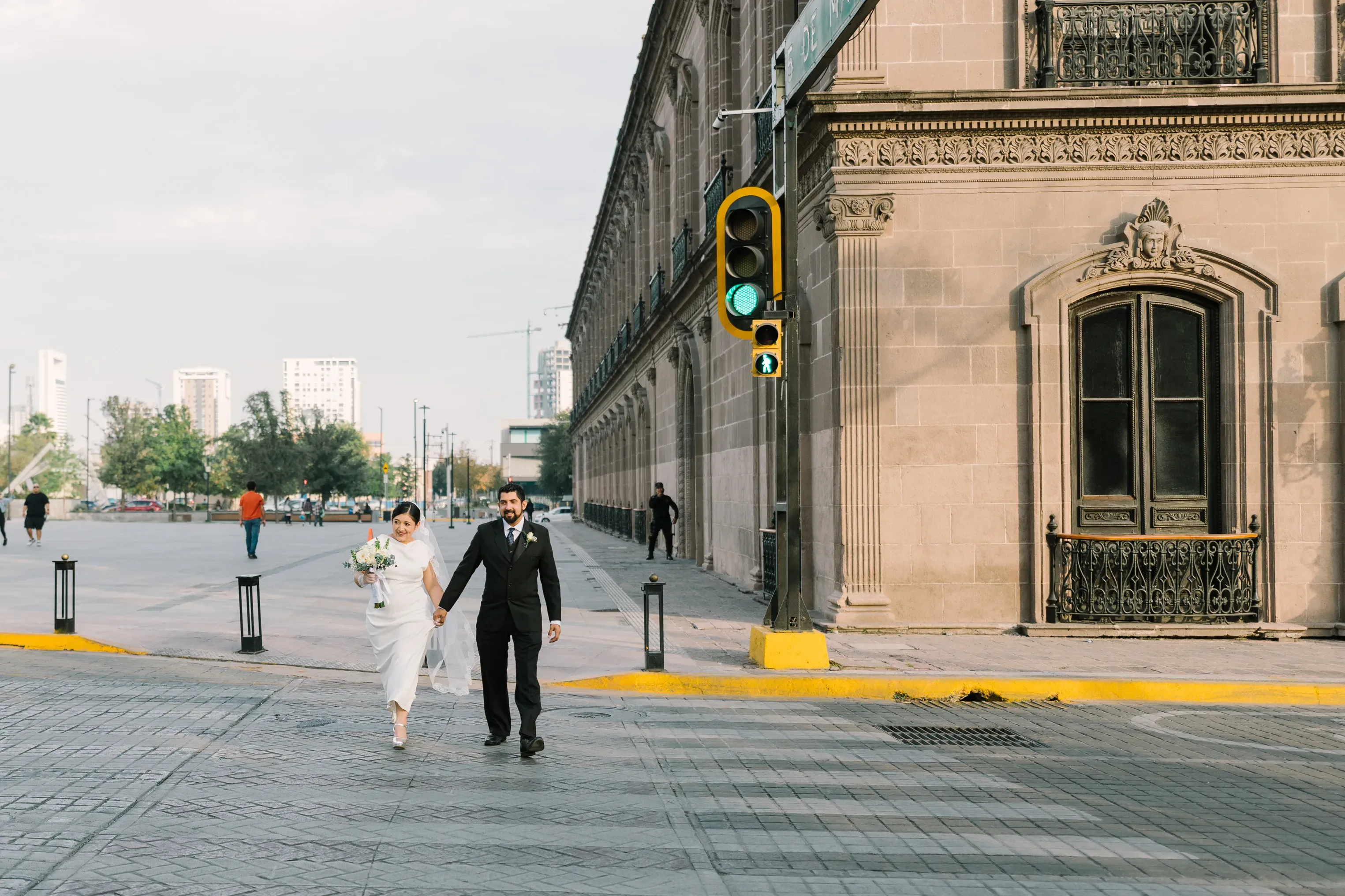 Amy y Jorge cruzando en esquina con semáforo en verde junto a edificio histórico del centro de Monterrey